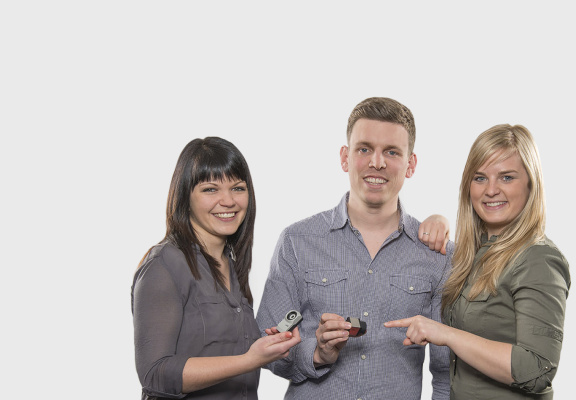 A picture of three IDS employees on a white background with an IDS camera in their hands.