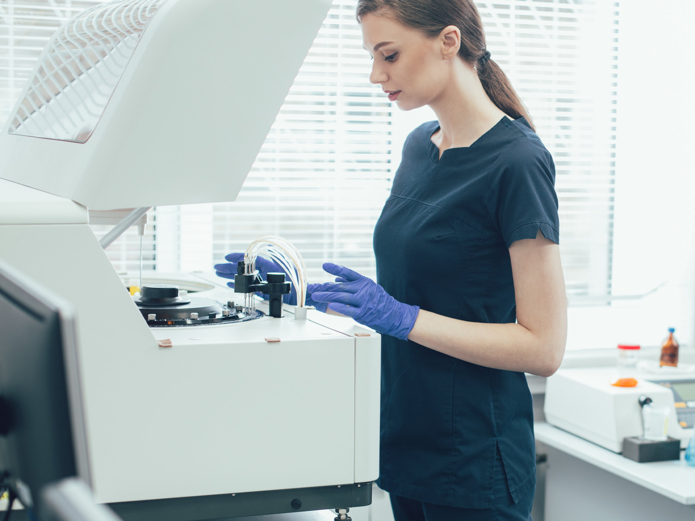 A woman in the laboratory puts a diagnostic device into operation with the help of an IDS uEye+ XLE camera.