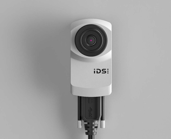 The IDS uEye XC camera from the front, connected with a cable.