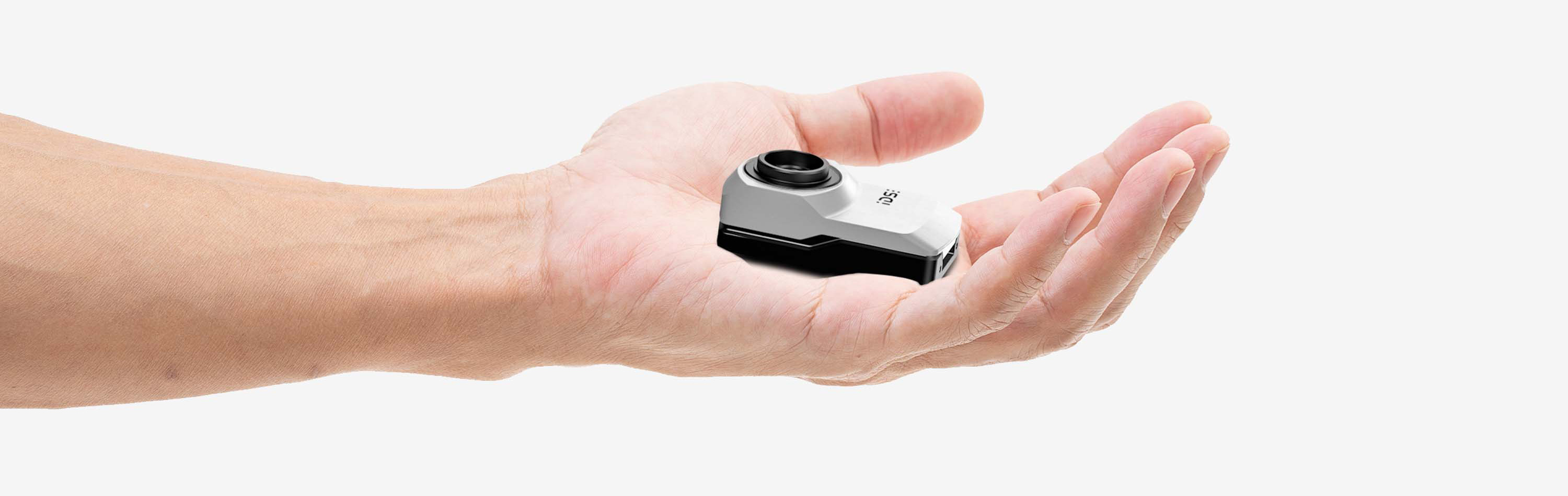 An IDS uEye XC camera lies in an open hand.