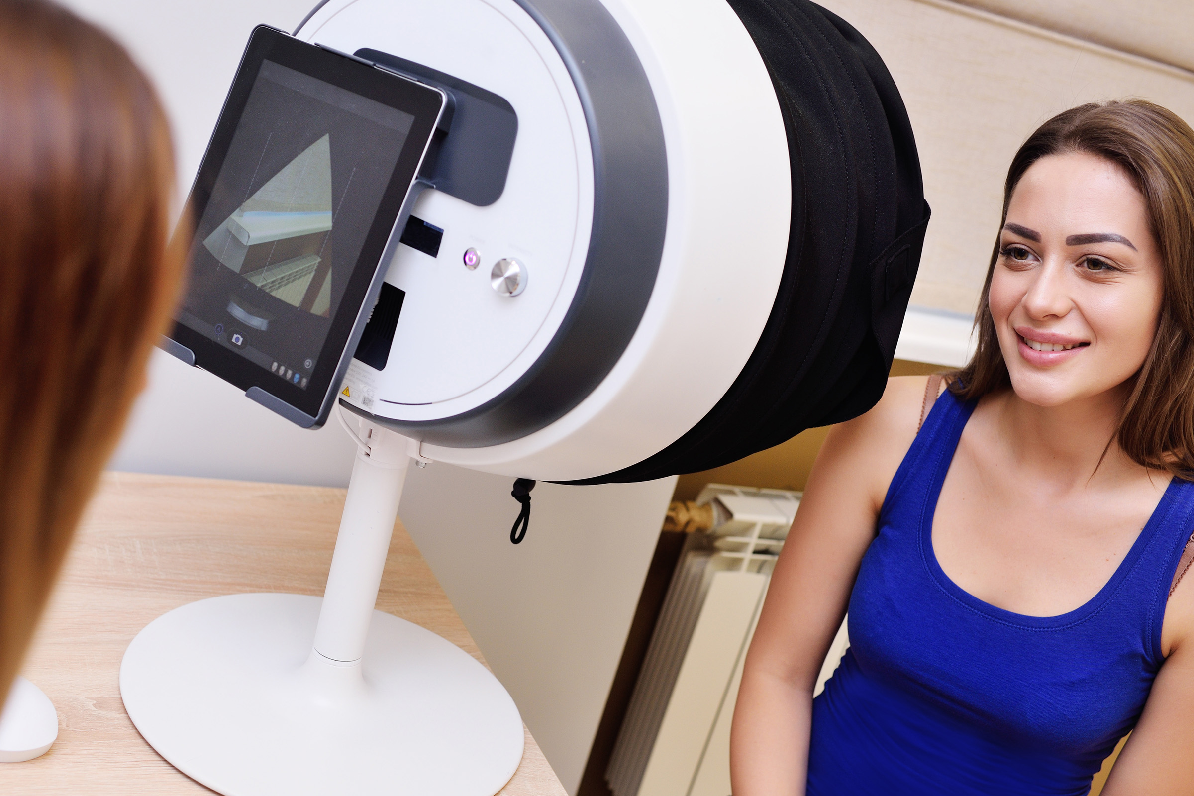 Woman sitting in front of a medical device equipped with a tablet on the back